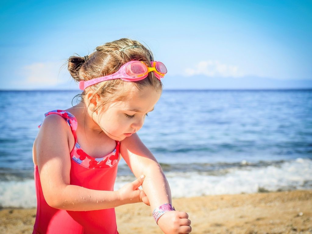enfant appliquant la crème solaire pour se protéger des effets nocifs du soleil